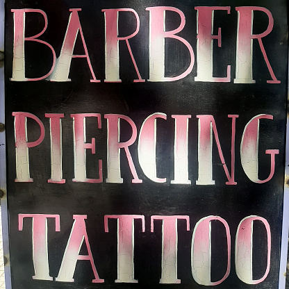 Chalkboard sign advertising barber, piercing and tattoo.