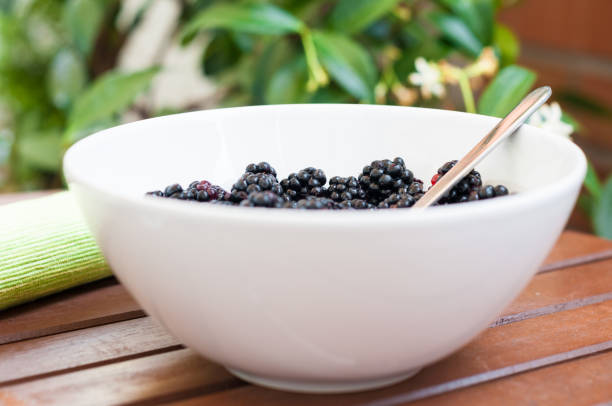 An arrangement of freshly picked blackberries in a rustic wooden bowl, showcasing the beauty and nourishment of nature's superfood