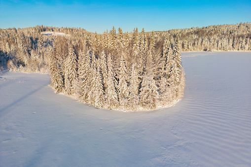 Aerial view of a gold sunset over winter snow-covered forest. Aerial drone view of a winter landscape. Beautiful sunset sky over frozen lake.