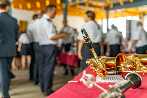 Castilla La Mancha, Spain. Close-up of a saxophone mouthpiece, with members of the local music orchestra chatting in the background during the celebration of a feast at the town's patron saint festival.