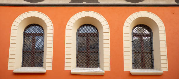 istock Three windows with iron grating on stone red wall. Old windows with ornamented metal lattice 1947547140