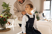 Responsible good father braiding little daughters hair, preparations for school