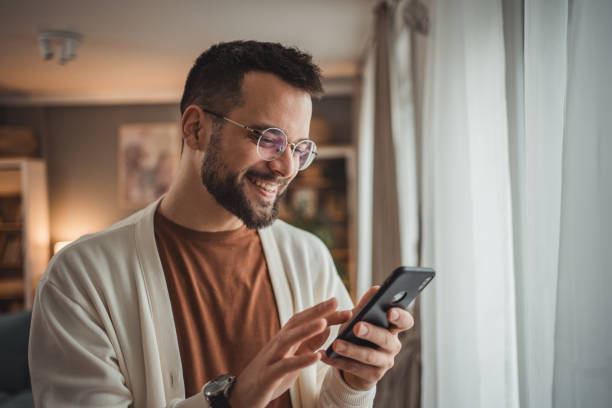 Portrait of cheerful man using smartphone at home, daily routine