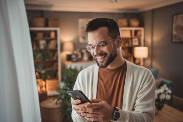 istock Portrait of cheerful man using smartphone at home, daily routine 1947568030