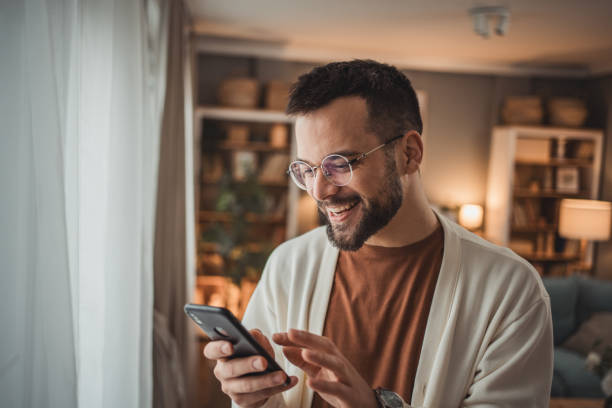 istock Portrait of cheerful man using smartphone at home, daily routine 1947568042
