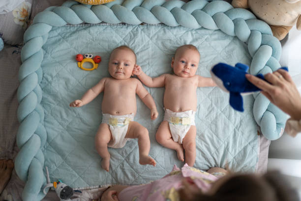 Twin baby brothers enjoying playing with mother early in the morning