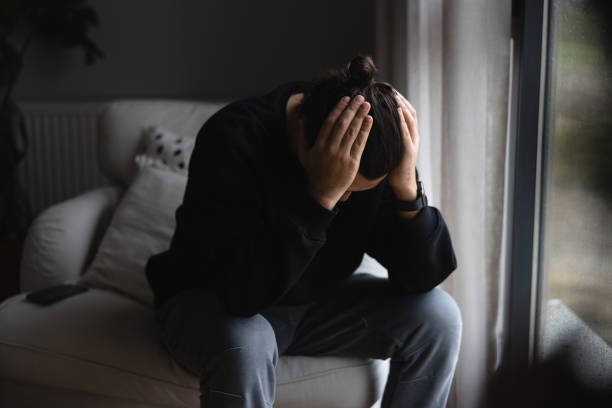 istock Young man at home looking out of window 1947610614