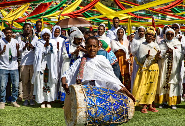 un niño toca el tambor y personas vestidas de blanco cantan oraciones, durante las celebraciones de la epifanía etíope (conocida como timket o timkat), addis abeba, etiopía - african descent drum african culture day fotografías e imágenes de stock