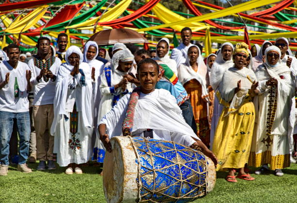 A young boy is playing the drum and people dressed in white are chanting prayers, during Ethiopian Epiphany (known as Timket or Timkat) celebrations, Addis Ababa, Ethiopia Addis Ababa, Ethiopia - January 19, 2023: Choir of men and women perform hymns during Timkat celebrations and a boy is playing the drum.
Timket is an Ethiopian Orthodox Tewahedo Church celebration of Epiphany. It is celebrated on 19 January (or 20 in a leap year), corresponding to the 11th day of Terr in the Ge'ez calendar. On this day, crowds assemble together with priests who are carrying over their heads covered replicas of the "tabot"(a model of the Ark of the Covenant) wrapped in rich cloth and borne in procession on the head of the priests. addis ababa ethiopia photos stock pictures, royalty-free photos & images
