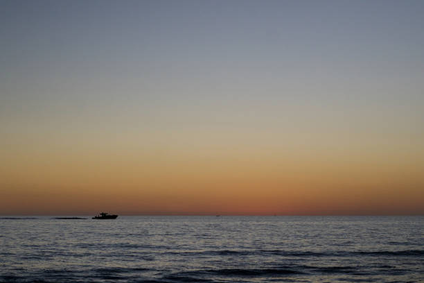 Three boats on the Gulf of Mexico with a sunset in the horizon.