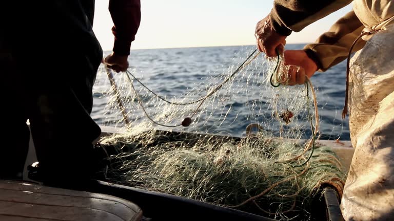 Fisherman at work with net on trawler fishing boat