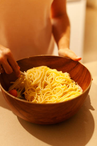 Mixing the spaghetti with the vegetables in a bowl