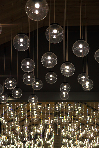 Round lamps hanging from ceiling in restaurant. Lamps decorated on the ceiling in restaurant. Celebrations in a restaurant. Original luxury decorative lighting in restaurant.