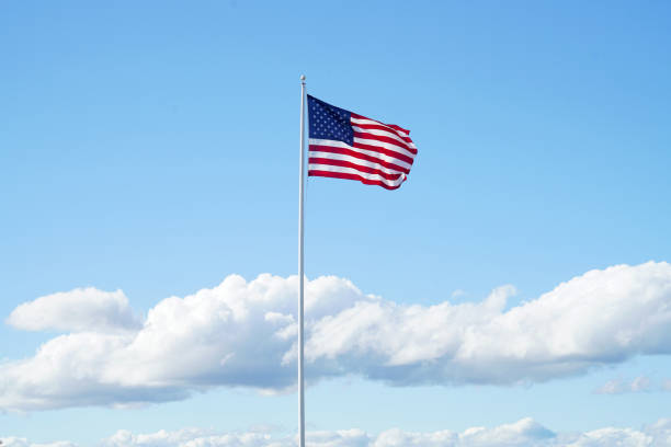 waving USA flag on pole against blue sky