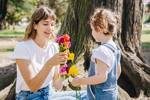 Girl giving a flower to mother in the public park
