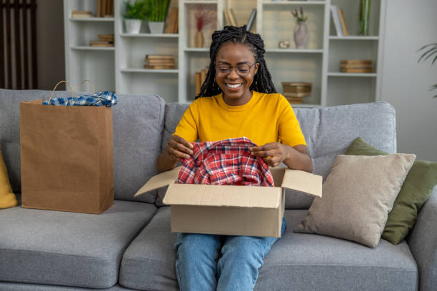 istock Smiling young woman opening a box with clothes 1947829624