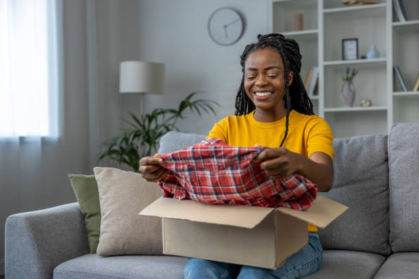 istock Young woman taking a checkered shirt from the box and smiling 1947829768