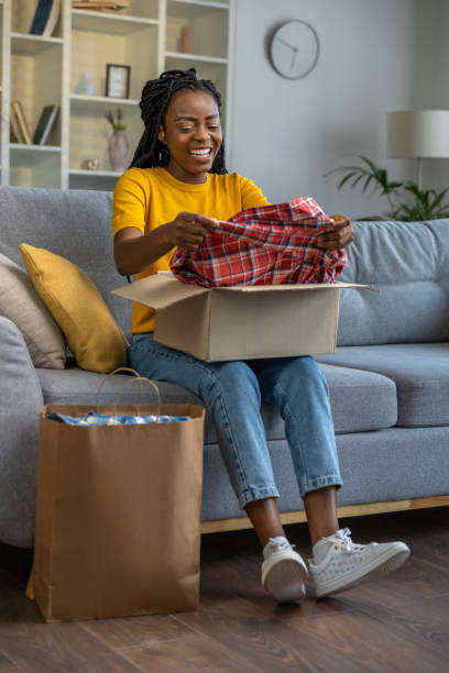 istock Smiling and happy woman looking contented while opening a box with clothes 1947830157