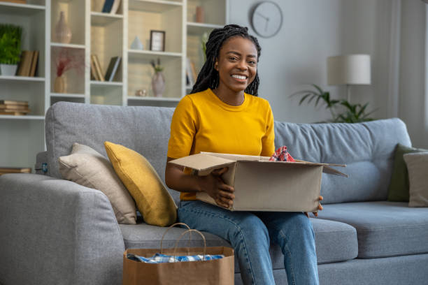 istock Smiling and happy woman looking contented while opening a box with clothes 1947830175