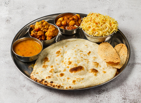 Vegetable thali set with plain biryani, mixed vegetable of aloo gobi matar, chanay, shorba and chapati served in dish isolated on background top view of indian spicy food
