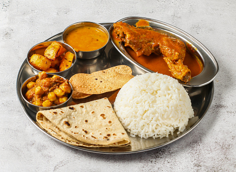 chicken thali set with chicken korma, chanay, plain rice, aloo, shorba and chapati served in dish isolated on background top view of indian spicy food
