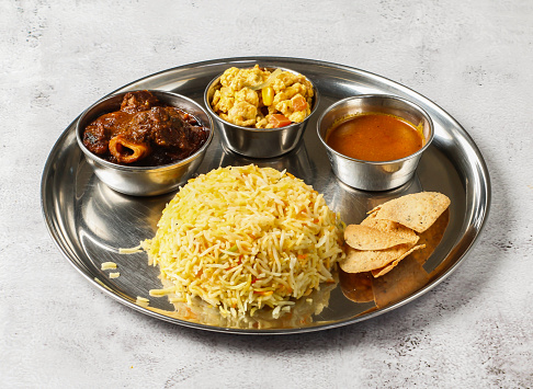 Mutton biryani thali set with korma karahi, mixed vegetable of aloo gobi matar, nachos and shorba served in dish isolated on background top view of indian spicy food