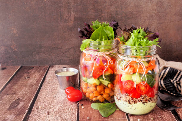Healthy mason jar salads, table scene on dark background