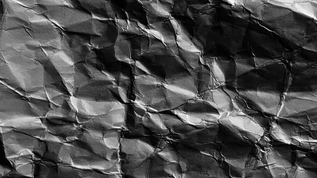 Crumpled Black Paper or Coal Background Texture Loopable Animation 4K Video. Stop Motion Effect Style.