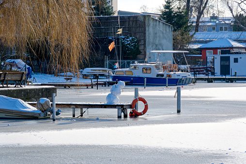 Winter scene with a snowman on a jetty at the Dahme river in Berlin Koepenick.