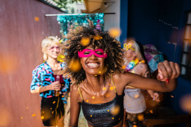 portrait of a young woman enjoying carnival with friends at home - carnival mask women party foto e immagini stock