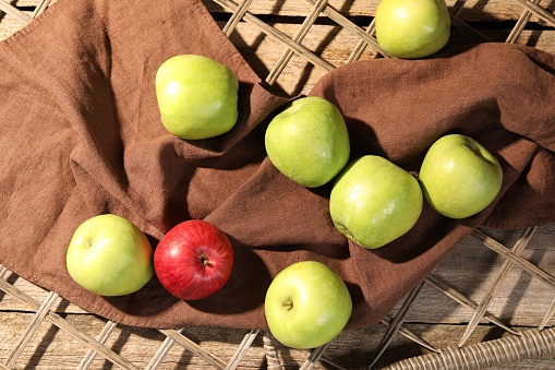 Fresh colorful apples on rattan grid, flat lay