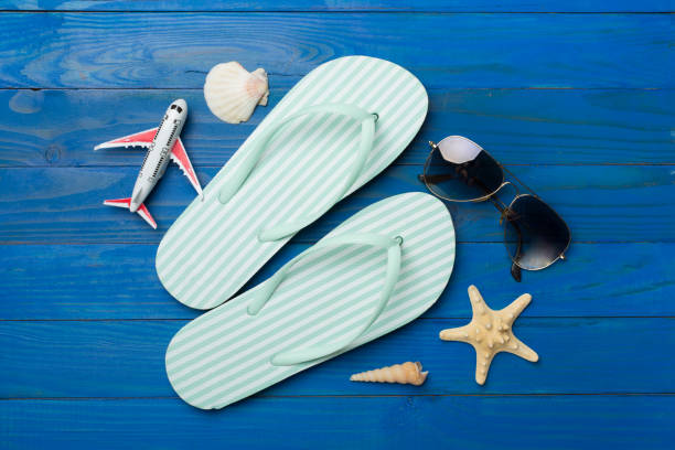 istock Flip flops with sunglasses and airplane on wooden background, top view 1947973521