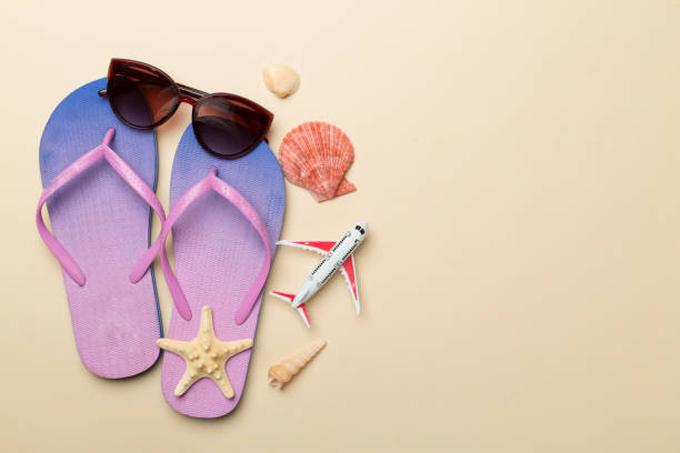 istock Flip flops with sunglasses and airplane on color background, top view 1947974034