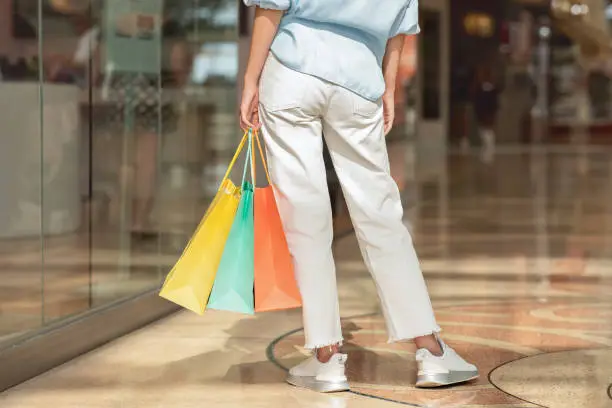 Millennial european lady in casual with many shopping bags in hand, look at shopwindow enjoy fashion shopping walk in mall, cropped. Shopaholic at sale, ad and offer, discount season