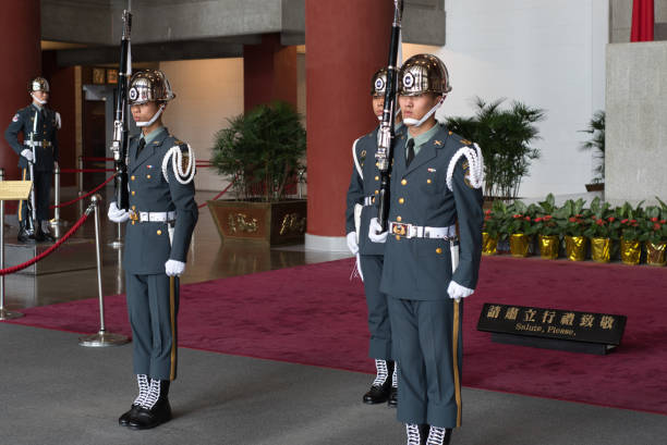 Uniformed honor guards standing at attention in a formal setting with ceremonial rifles.
