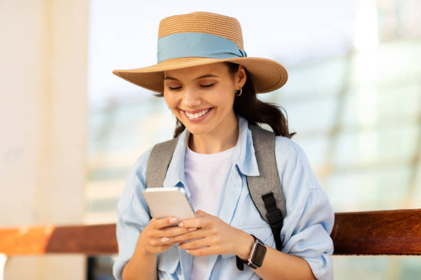 istock Happy young european lady tourist in hat with backpack, typing on smartphone, use online map, chatting 1948000049