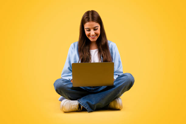 istock Glad caucasian teenager student lady use computer, typing and sit on floor 1948014583