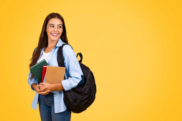 istock Positive pretty young student lady with backpack and books look at copy space 1948014590