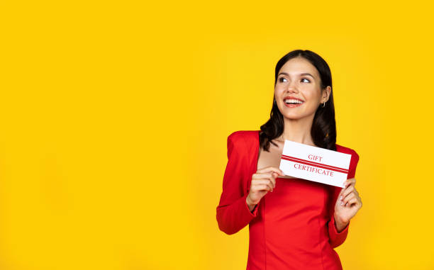 istock Happy Young Woman Holding Gift Certificate And Looking Aside At Copy Space 1948024512