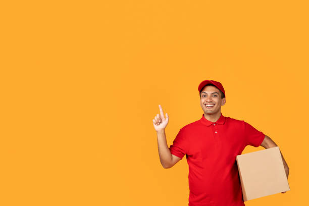 istock Arab courier guy holds cardboard box and pointing aside, studio 1948033857