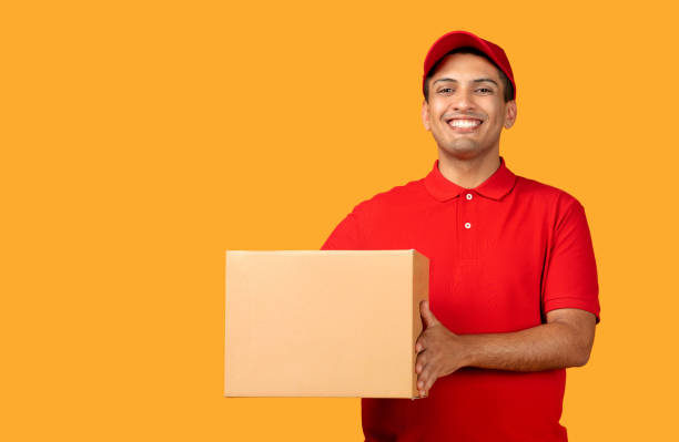 istock deliveryman confidently holding cardboard box stands over yellow studio background 1948033859