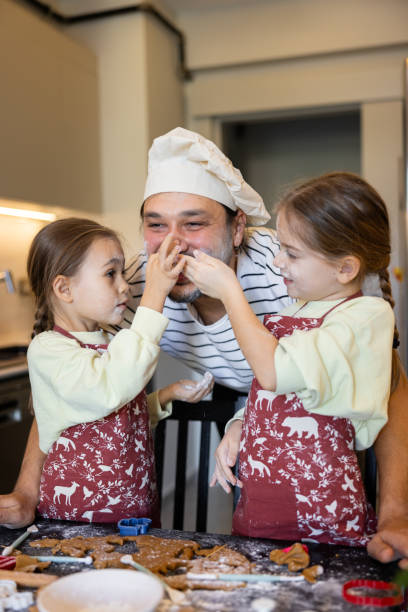 istock Sisters having a fun time in the kitchen while helping the father to make Christmas cookies 1948043225