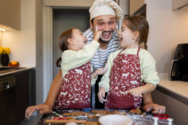 istock Sisters having a fun time in the kitchen while helping the father to make Christmas cookies 1948054678
