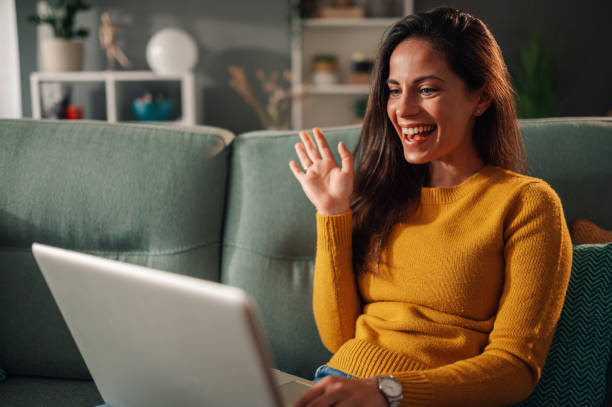 istock Woman using laptop and having a video call while sitting on couch at home 1948062946