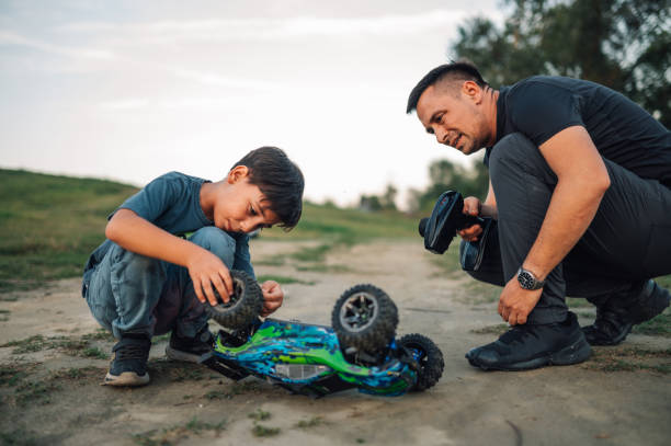 istock Son and dad checking their overturned and broken toy car outdoors. 1948063468