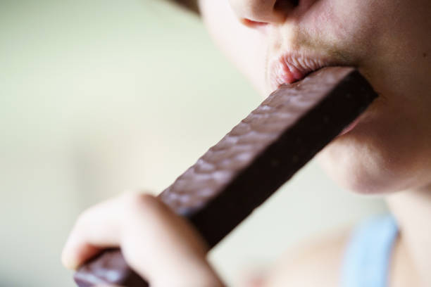 istock Crop anonymous young girl eating chocolate protein bar 1948068649