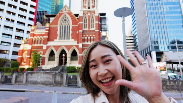 Young Japanese woman holding and talking with camera as influencer travel vlogging at the city