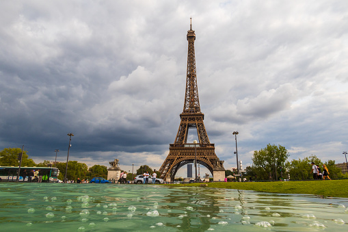 Paris, France - August 29 2023: Tourists and Eiffel tower seen from Trocadero Fountains in a cloudy day. Photography taken in Paris.
