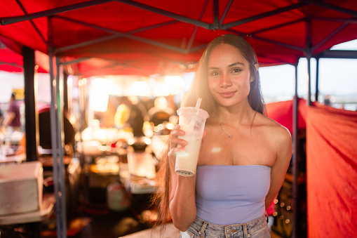 Pacific Island woman enjoying a drink in a make shift market in Auckland, New Zealand.