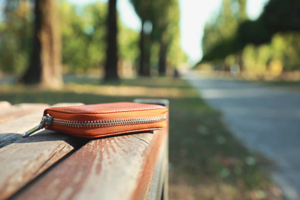 istock Brown leather purse on wooden bench outdoors, space for text. Lost and found 1948208204